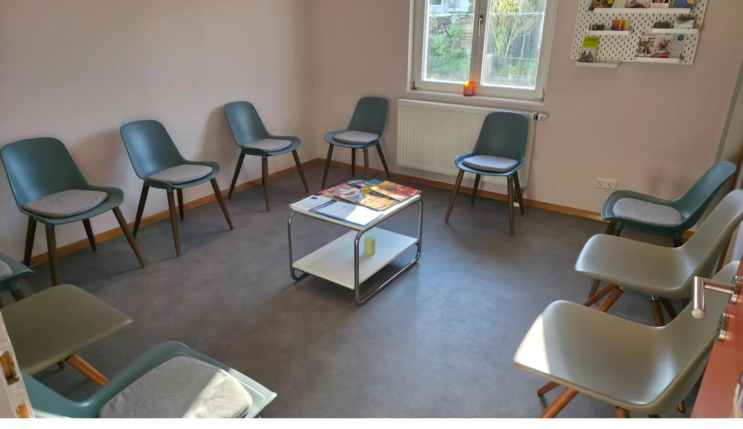 Wartezimmer der Praxis mit petrolfarbenen Stühlen und Zeitschriftentisch